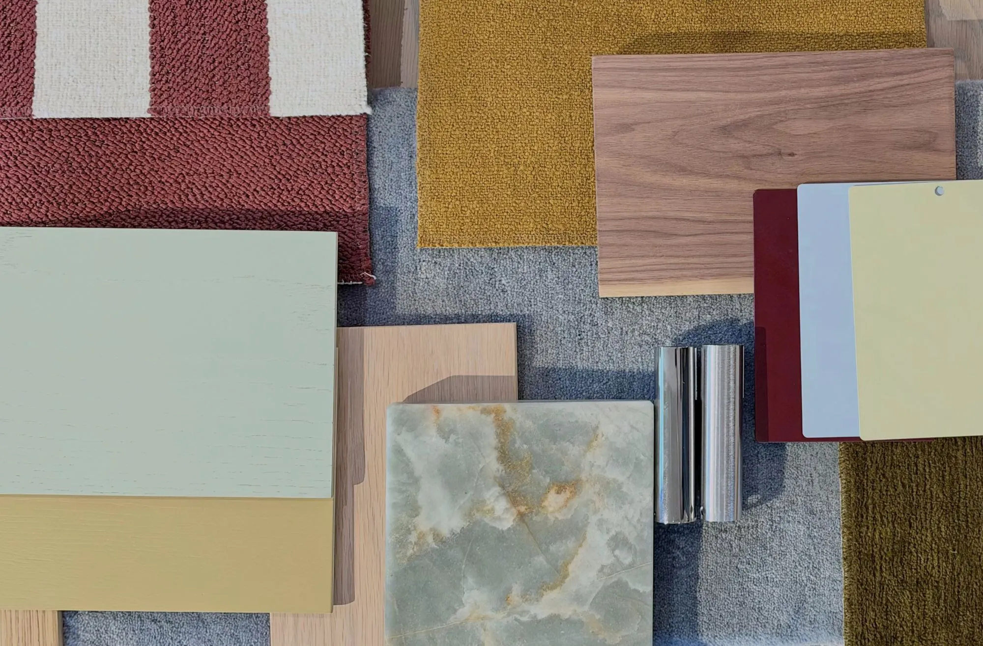 Material samples for a Concept Consult, including red and mustard carpet, walnut and oak, sage and ochre painted timber, green onyx and polished steel.